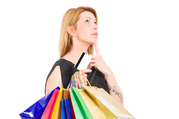 Mulher de compras segurando cartão de crédito ou débito e pensando — Fotografia de Stock