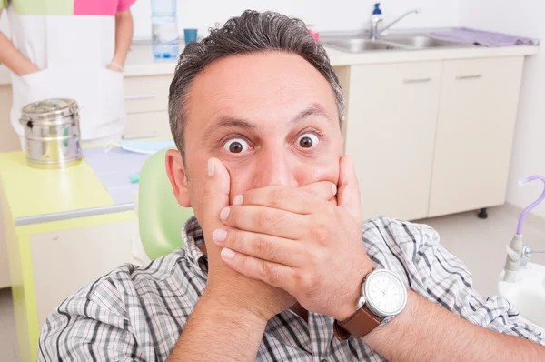 Przerażony człowiek u dentysty obejmujące jego usta — Zdjęcie stockowe