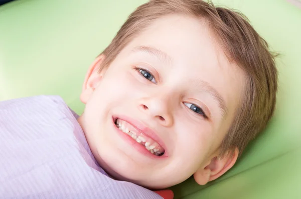 Criança sorridente com rosto feliz na cadeira ou no escritório do dentista — Fotografia de Stock