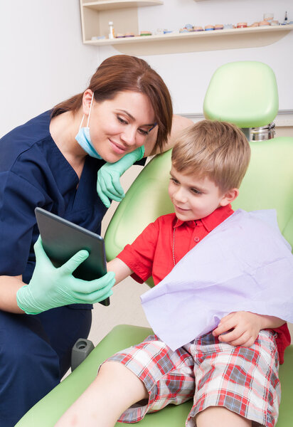Happy kid patient at dentist using wireless tablet