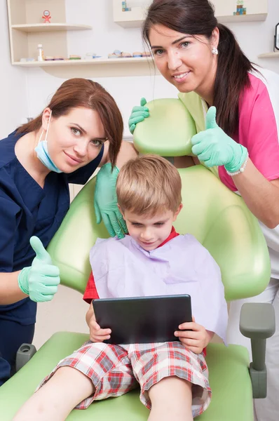 Happy kid at dentist playing with wireless tablet — Stockfoto