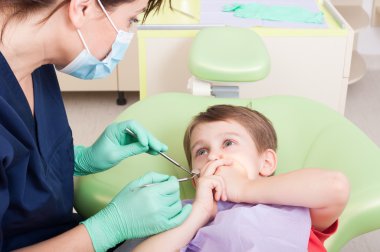 Scared kid in dentist office covering mouth