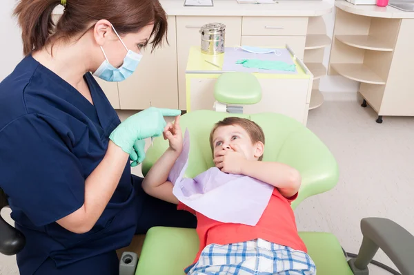 Woman dentist calming kid patient with games — Stockfoto