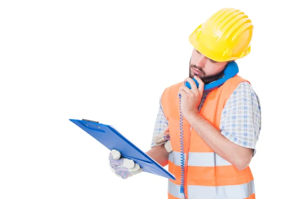 Busy contractor using phone while holding clipboard — Stock Photo, Image