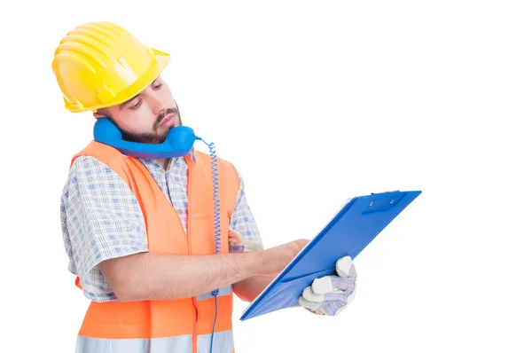 Busy builder using phone while holding clipboard — Stock Photo, Image