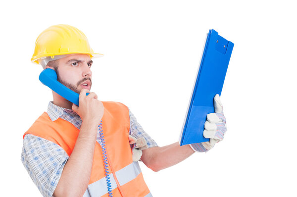 Confident contractor or builder using phone and holding clipboar