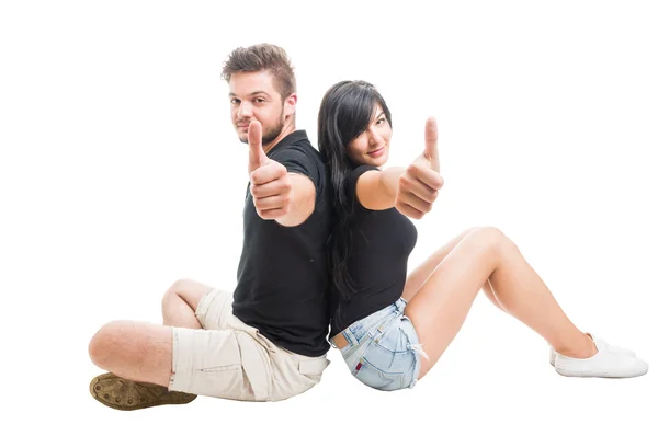 Happy couple sitting back to back and showing like — Stock Photo, Image