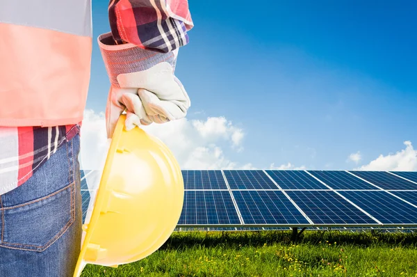 Engineer holding hardhat on solar power photovoltaic panels back — Stock Photo, Image