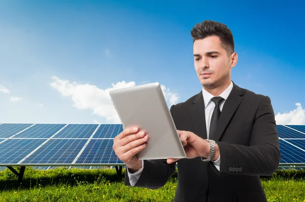 Zakenman bedrijf draadloos tablet op zonne-energie panelen backgr — Stockfoto