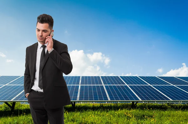Empresário falando ao telefone em painéis de energia solar backgroun — Fotografia de Stock