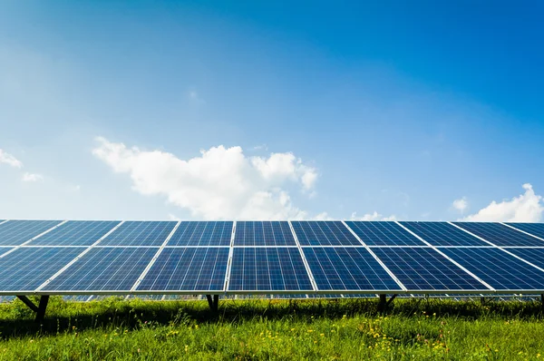 Solar panels on green field and blue sky — Stock Photo, Image