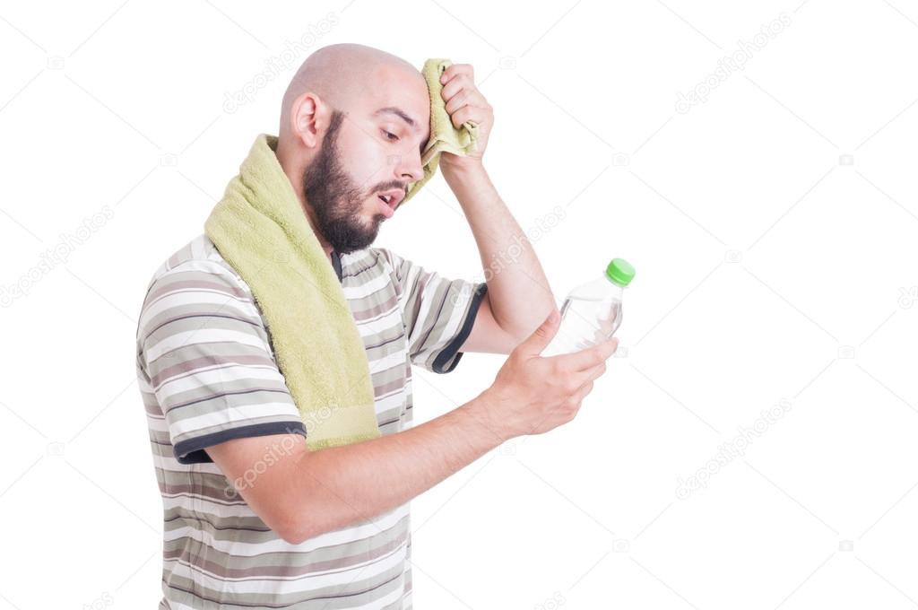 Dehydrated man wiping forehead and holding bottle of water
