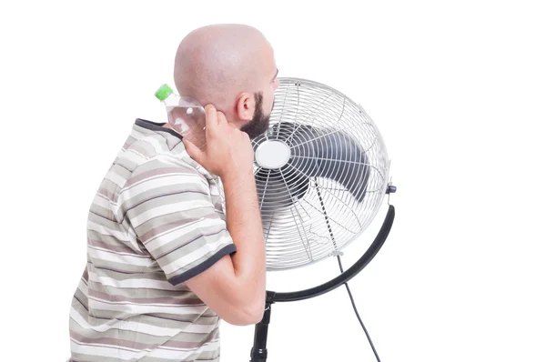 Man cooling down with blowing fan and cold water — Stock Photo, Image