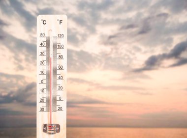 Thermometer on ocean or sea sunset background clipart