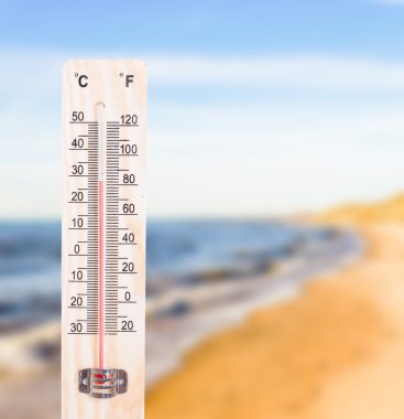 Thermometer on sunny beach background clipart