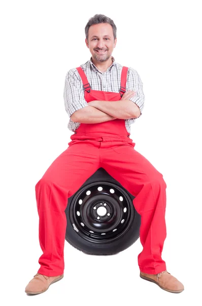 Mecânico confiante sentado no pneu da roda do carro — Fotografia de Stock