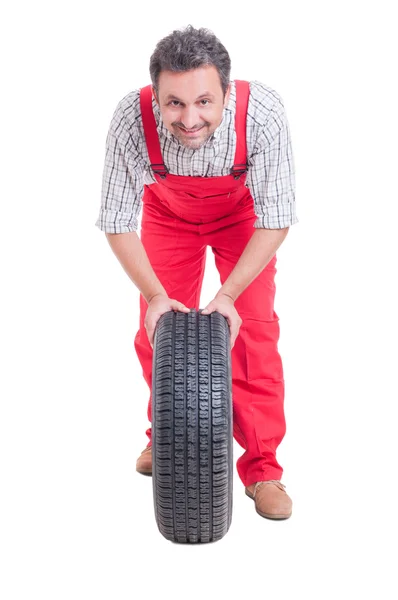 S úsměvem mechanik tlačit auto kola s pneu — Stock fotografie