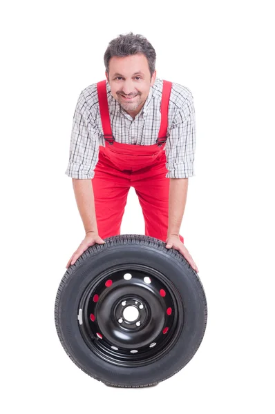 Mécanicien souriant et roue de voiture avec pneu noir — Photo