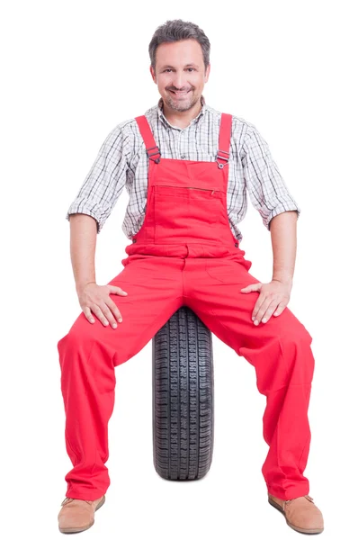 Trots en vol vertrouwen mechanic zittend op auto wielen — Stockfoto