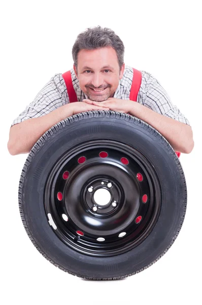 Smiling mechanic resting head on tire — Stock Photo, Image