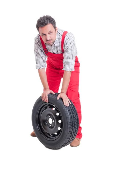 Tired mechanic resting on car wheel — Stock Photo, Image