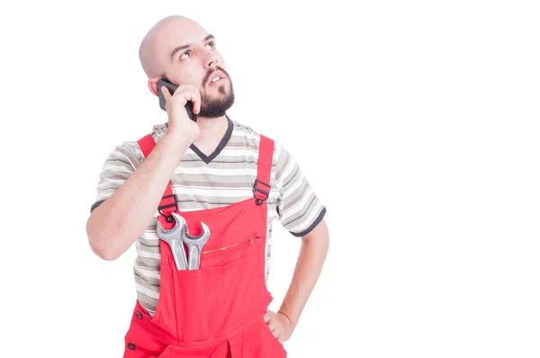 Young  mechanic talking on the phone looking up — Stock Photo, Image