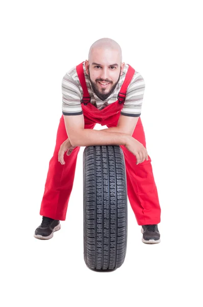 Felice meccanico appoggiato su una nuova ruota dell'auto — Foto Stock