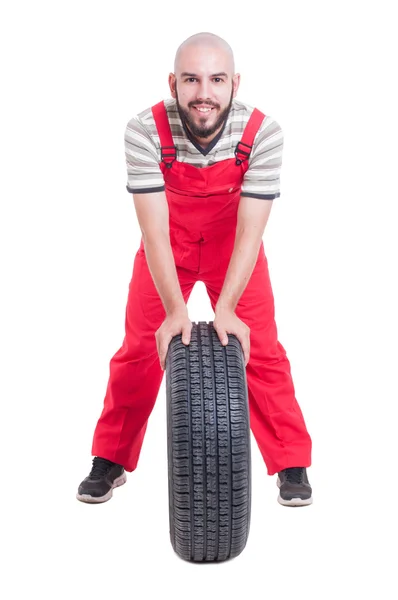 Mécanicien souriant reposant sur une nouvelle roue de voiture — Photo