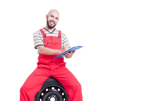 Lächelnder Mechaniker mit freundlichem Gesicht, der ein Klemmbrett hält — Stockfoto