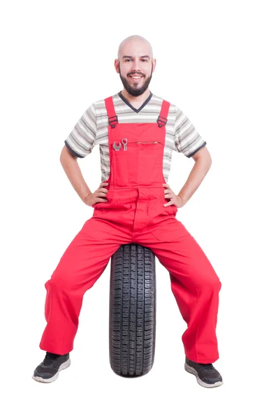 Joyeux mécanicien assis sur la roue de la voiture — Photo