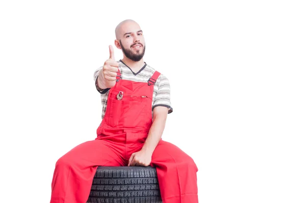 Jonge mechanic zittend op auto wiel en weergegeven als: — Stockfoto