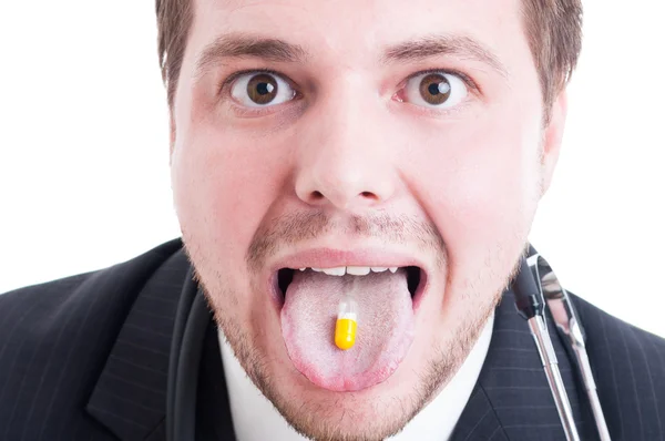 Мужчина врач или медик, принимающий таблетки на языке — стоковое фото