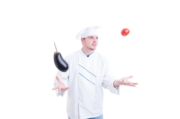 Chef ou cuisinier jonglant avec des légumes une aubergine et tomate — Photo