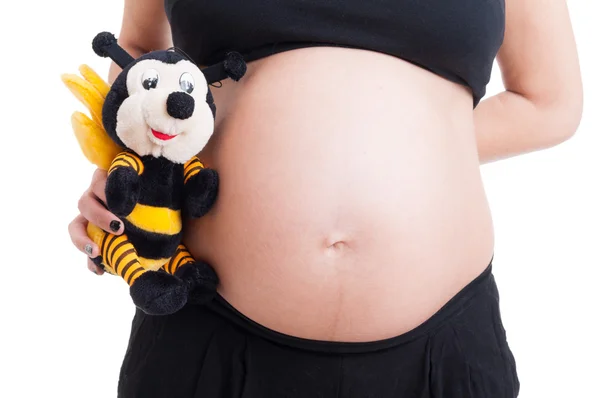 Велика вагітна жінка живіт і мила плюшева бджола іграшка — стокове фото