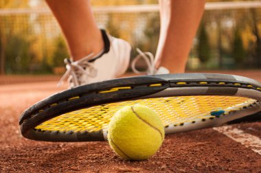 Tenis topu, örgü, raket ve kadın ayakları konseptiyle