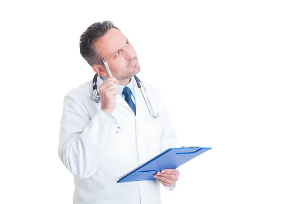 Smart doctor or medic holding clipboard and thinking — Stock Photo, Image