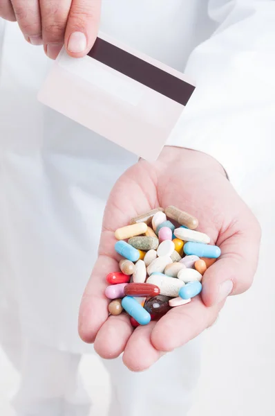 Врач-фармацевт или медик держит в руках таблетки и кредитную карту — стоковое фото
