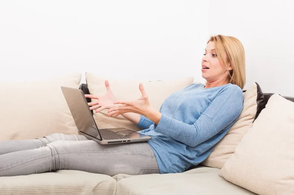 Donna sorpresa che tiene il computer portatile in grembo a casa — Foto Stock