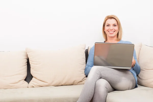 Lachende vrouw met laptop thuis op de Bank — Stockfoto