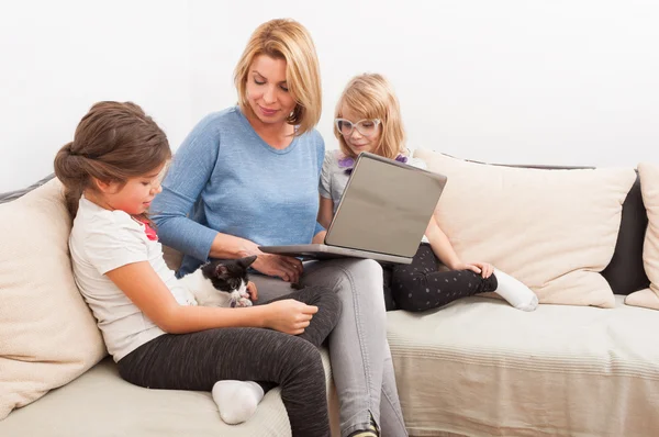 Giovane madre con due belle figlie utilizzando il computer portatile — Foto Stock