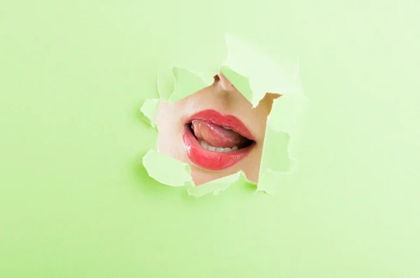 Sexy bouche féminine portant rouge à lèvres à travers trou de papier déchiré — Photo