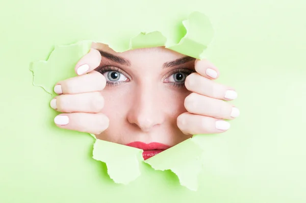 Schöne Frau schaut durch zerrissene grüne Pappe — Stockfoto