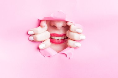 Sevimli kadın güzel gülümseme yırtık pembe karton aracılığıyla gösterilen