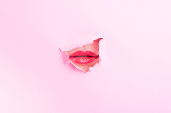 Woman mouth with red lips thru torn cardboard 