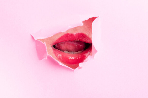 Sexy woman mouth with lipstick thru pink ripped board