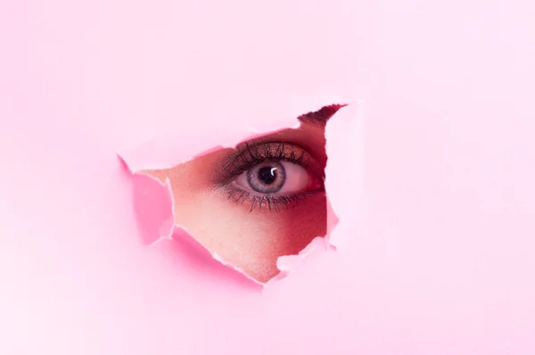 Olho feminino com maquiagem olhando thru cortar papelão — Fotografia de Stock