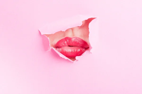 Привлекательный женский рот, разделяющий поцелуй через разорванную бумажную дыру. — стоковое фото