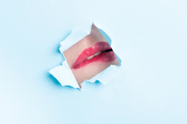 Γυναίκα που δαγκώνει τα χείλη της μέσα από την τρύπα σχισμένο χαρτί — Φωτογραφία Αρχείου