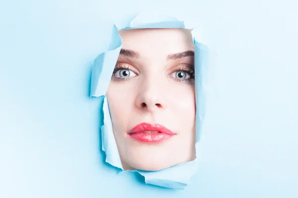 Young woman face looking thru torn cardboard — Stock Photo, Image