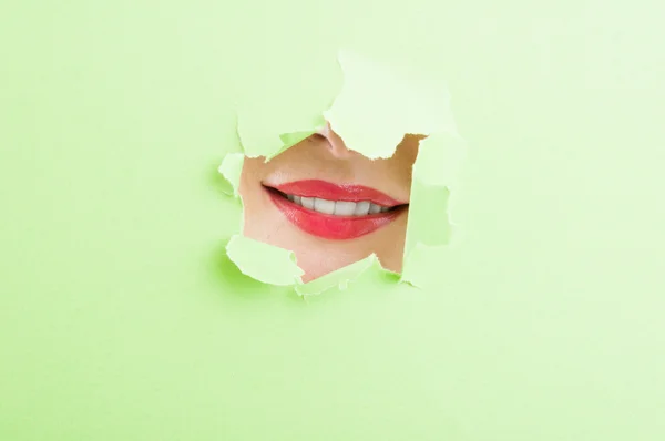 Bela boca feminina mostrando um sorriso através de papelão rasgado — Fotografia de Stock